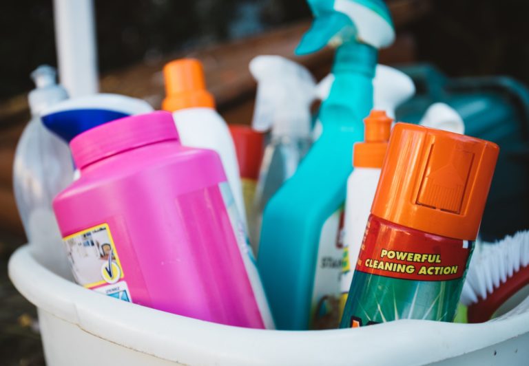A bucket with colorful cleaning supplies inside