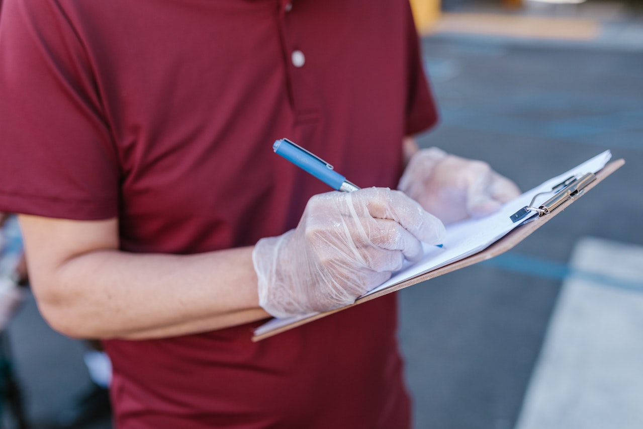 A photo of a cleaner wearing gloves, ticking off a checklist.