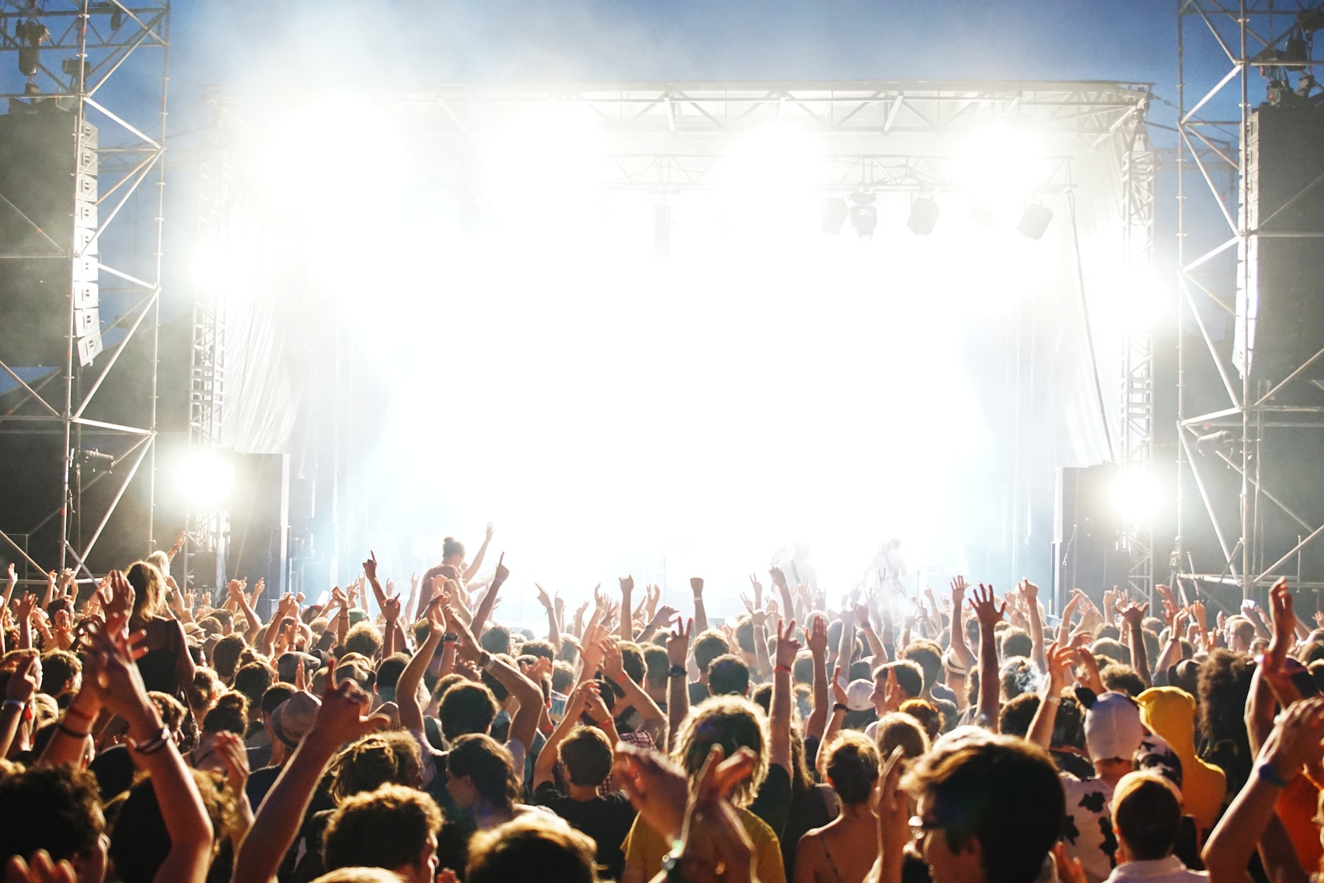 A crowd of people cheering a stage at a festival.