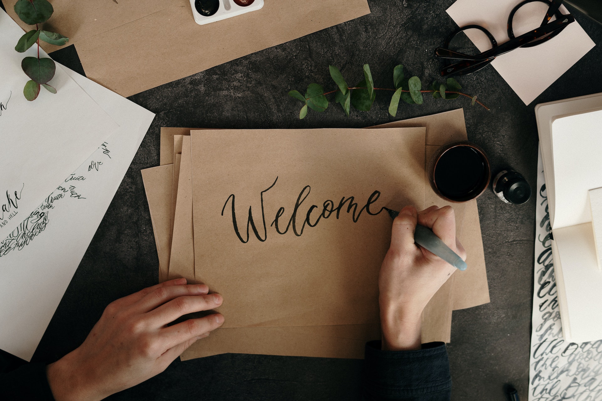 A view from above of a woman writing Welcome on a piece of craft paper