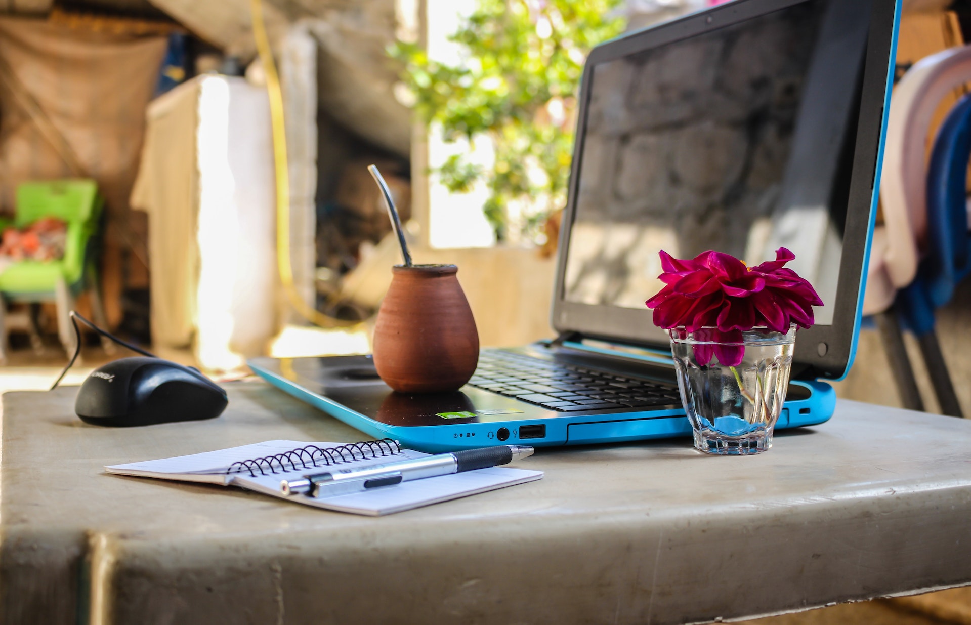 A laptop on a coffee shop table with a drink outdoors